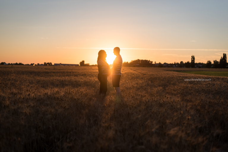Photographe de grossesse à Toulouse, la silhouette des futurs parents et du ventre rond au coucher de soleil dans un champ de blé