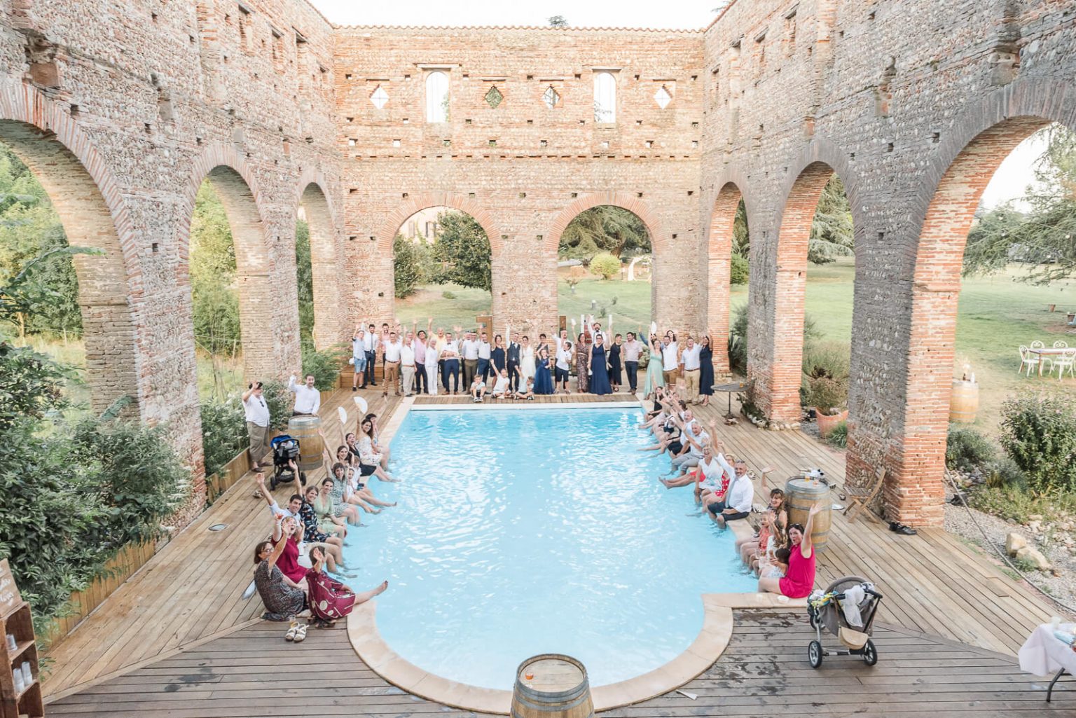 Photographe de mariage au Domaine du Beyssac et photo de groupe autour de la piscine les pieds dans l'eau