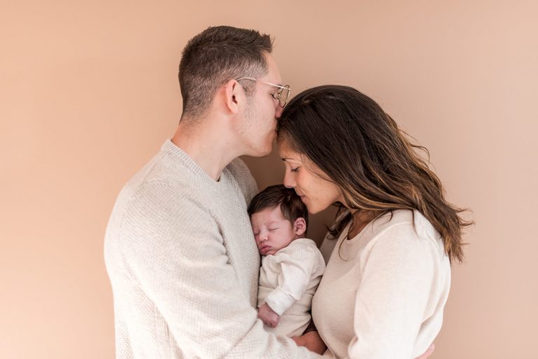 Photo de bébé dans les bras de ses parents lors d'une séance photo de naissance à domicile à Toulouse
