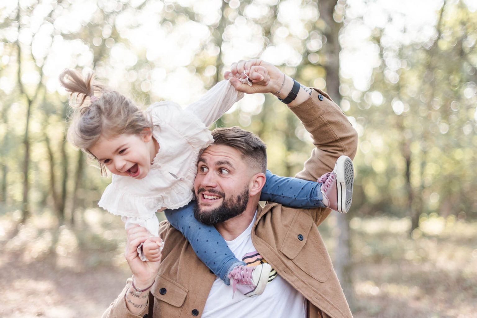 Séance photo de famille en forêt à La Ramée près de Toulouse, petite fille riant sur les épaules de papa