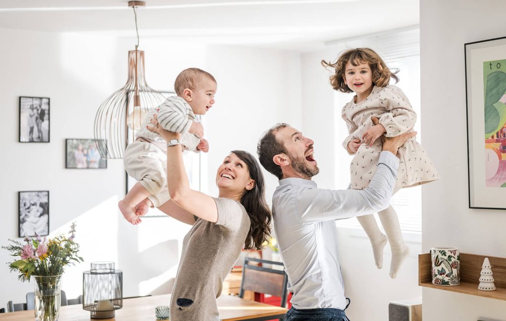 Parents qui font sauter leurs enfants dans leurs bras lors d'une séance photo en intérieur à Toulouse