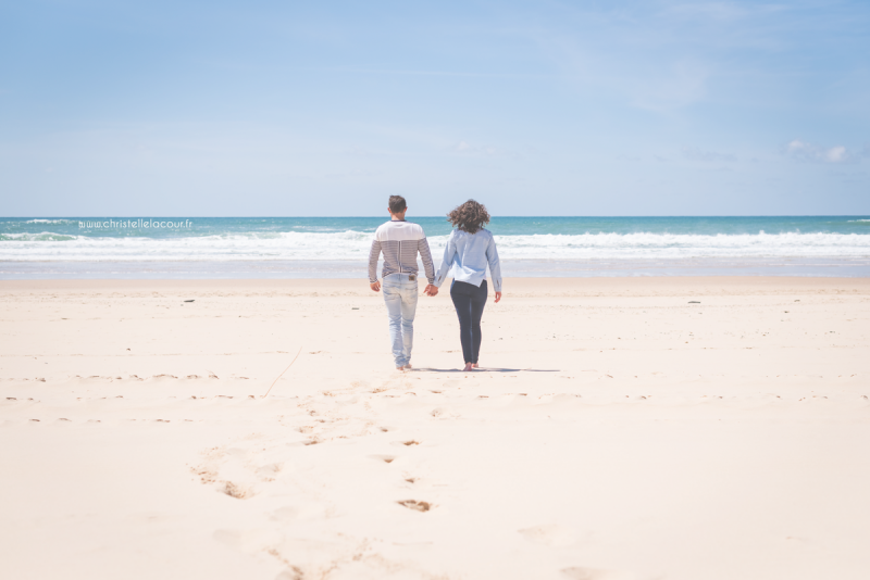 Couple d'amoureux s'avançant vers les vagues sur un plage de l'Atlantique