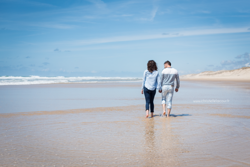 Amoureux marchant main dans la main et les pieds dans l'eau sur la plage de Lacanau