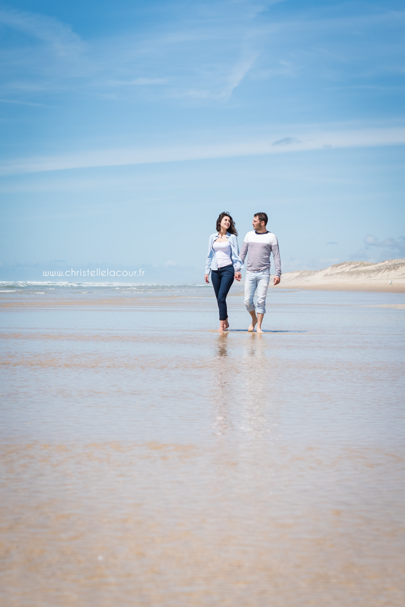 Amoureux marchant main dans la main et les pieds dans l'eau sur la plage de Lacanau