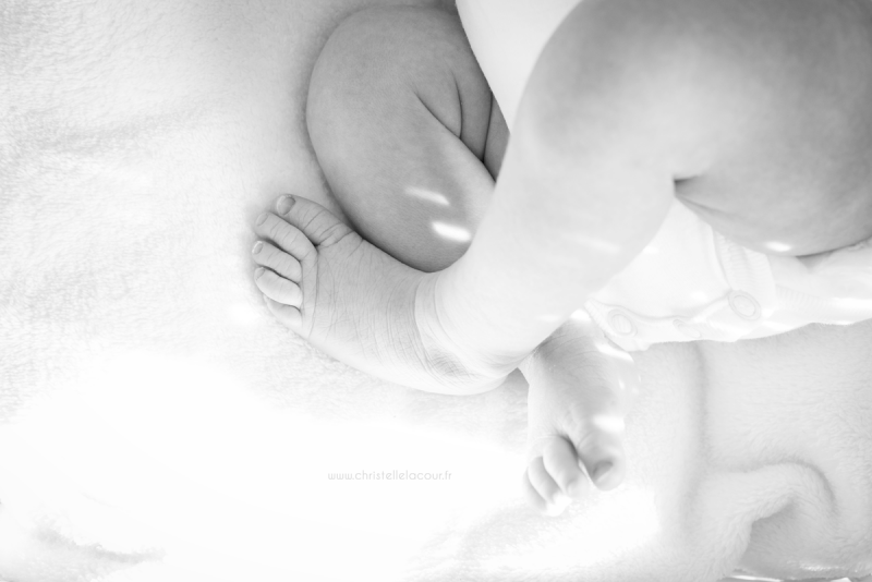 Photo nouveau-né à domicile, petites jambes de bébé croisées