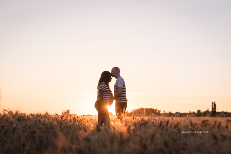Photographe de grossesse à Toulouse, futurs parents et ventre rond à la lumière du coucher de soleil dans un champ de blé