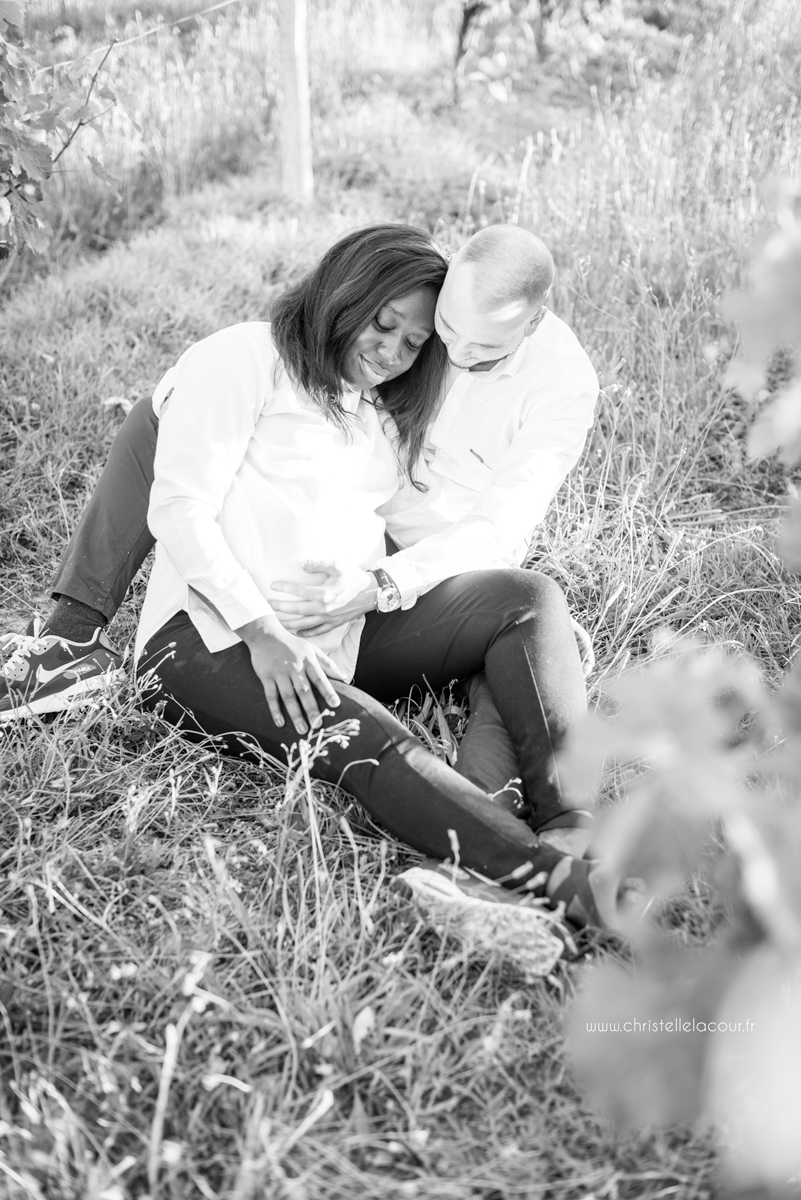 Séance grossesse à Toulouse, pause tendre pour ces futurs parents assis dans les vignes en noir et blanc