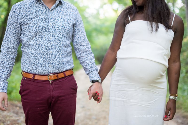 Séance photo de grossesse en couple dans la forêt, les futurs parents mains dans la main