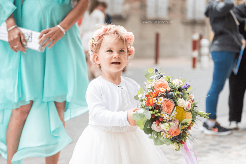 Photographe de mariage à Toulouse au Domaine Beausoleil, la fille des mariés, fière de tenir le bouquet de sa maman