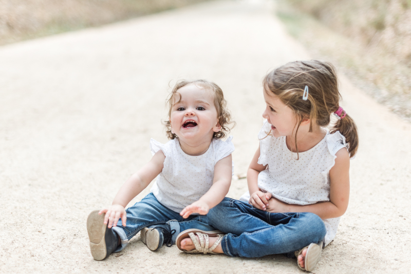 Photo de deux sœurs assises dans un chemin lors d'une séance photo de famille en forêt de Buzet près de Toulouse