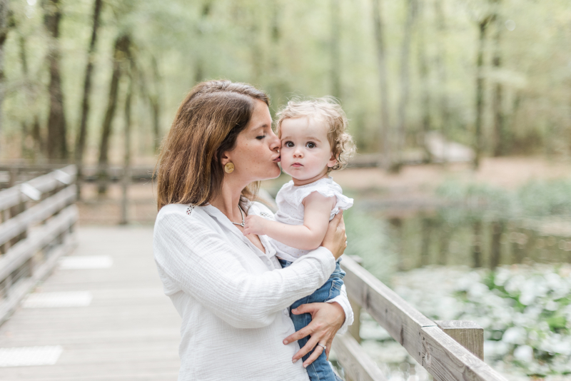 Photo de petite fille d'un an dans les bras de sa mère en forêt de Buzet près de Toulouse